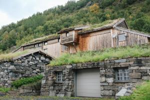 勒尔达尔Ein heilt spesiell låve i Røldal的一座石头建筑,设有草地屋顶和车库