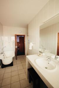 斯瓦科普蒙德Hotel Schweizerhaus/Cafe Anton的浴室配有2个盥洗盆、浴缸和浴缸。