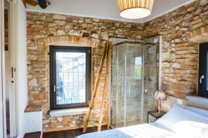 代森扎诺-德尔加达Villa Colli Storici的卧室设有石墙,窗户旁设有梯子