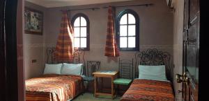 马拉喀什Hotel Wissam的一间卧室设有两张床和两个窗户。