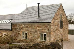 哈罗盖特Squeak Cottage的石屋,设有灰色的屋顶和窗户