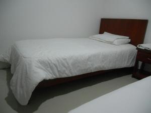 BaranoaHotel Manzanares Baranoa的卧室配有白色的床和木制床头板