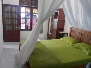 姆杜克Jojo's Warung & Homestay的一间卧室配有一张带天蓬的绿色床
