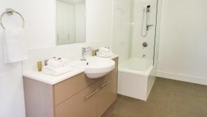汤斯维尔Oaks Townsville Gateway Suites的白色的浴室设有水槽和淋浴。