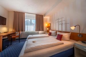 上茨豪森Parkhotel Obertshausen的酒店客房配有两张床和一张书桌