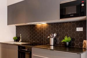 瓦伦西亚Ramirez Flats Valencia的厨房配有不锈钢用具和黑色瓷砖墙