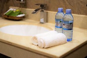 恩德培恩德培最佳西方精品花园酒店的浴室水槽配有2瓶水和1条毛巾