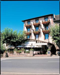 圣让皮耶德波尔比利牛斯酒店的大楼前有桌子和遮阳伞的酒店