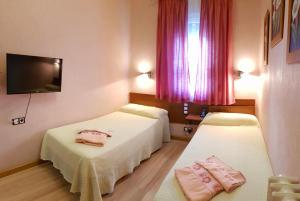 巴利亚多利德Hostal De La Torre Hostal Economico的两张位于酒店客房的床,配有粉红色窗帘
