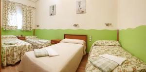 巴利亚多利德Hostal De La Torre Hostal Economico的一间设有两张床和绿色墙壁的客房
