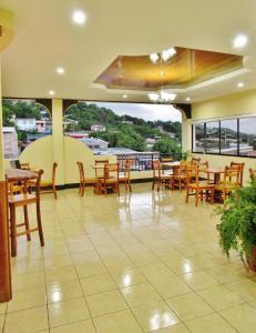 马塔加尔帕Hotel Palmeras de Elim的餐厅设有木桌、椅子和大窗户。