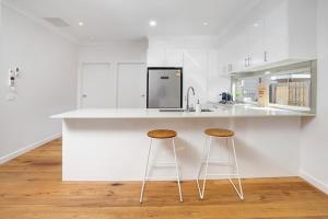Capel SoundStaughton Sounds的白色的厨房,配有两个吧台凳和台面