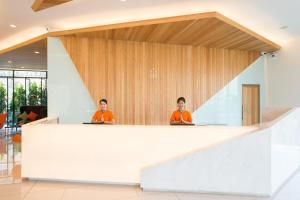 芭堤雅市中心J Inspired Hotel Pattaya - SHA Extra Plus的两人坐在大堂的柜台