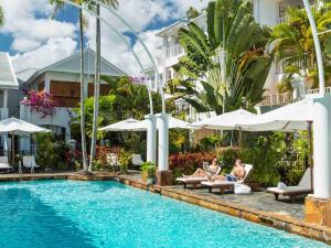 棕榈湾The Reef House Adults Retreat - Enjoy 28 Complimentary Inclusions的两个人坐在酒店游泳池边的椅子上