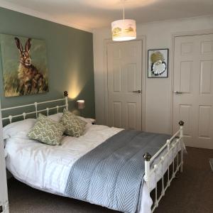 BlackfordThe Grey Cottage的卧室配有一张床,墙上挂着一幅兔子画