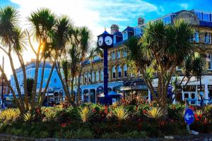 兰迪德诺Cornerhouse Apartments Llandudno的棕榈树建筑前的钟楼