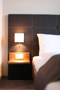明德尔海姆昆斯特慕勒酒店的一张带床头柜的床,上面有灯