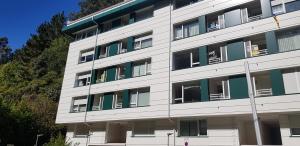 蒙达卡Mundaka Beach flat parking privado的一座白色的大建筑,设有绿色百叶窗
