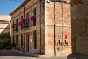 Villanueva de CampeánPosada Real del Buen Camino的砖砌的建筑,花朵呈紫色