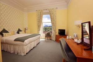 加拉希尔斯Kingsknowes Hotel的一间卧室配有一张床、一张书桌和一个窗户。