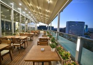 安卡拉Güvenay Business Hotel的阳台餐厅,配有桌椅