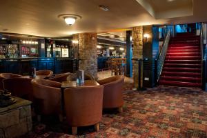 纽敦纳兹斯特兰福德纹章酒店的一间酒吧,配有棕色皮椅和楼梯