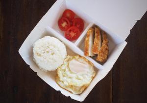 PaoayBalay Travel Lodge的桌上一盒饭,包括鸡蛋和西红柿