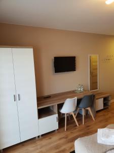 凯尔采Hotel Pod Strzechą的一间卧室配有一张桌子、一台电视和两把椅子