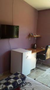 姆巴巴内Otentik guesthouse的一间设有一张桌子和一台墙上的电视的房间