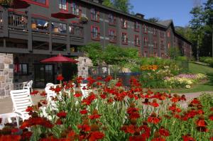 Sainte-Catherine杜切斯内旅游站酒店 - 瑟帕克的一座花园,在一座建筑前种有红色花卉