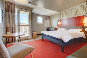 多维尔宜必思多维尔中心酒店的酒店客房设有一张大床和一张桌子。
