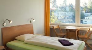 伯尔尼伯尔尼77号旅舍的一间卧室配有一张床、一张桌子和一个窗户。