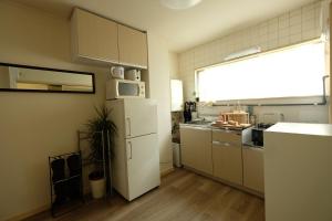 东京COCO Nakameguro 201的厨房配有白色冰箱和窗户。