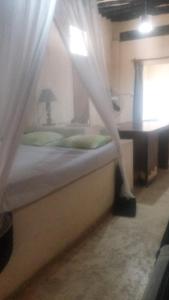 拉穆Wildebeeste Lamu的一间卧室配有一张带窗帘和桌子的床