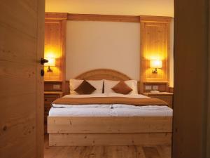科雷多Garni Le Maddalene的一间卧室配有一张大床和木制床头板