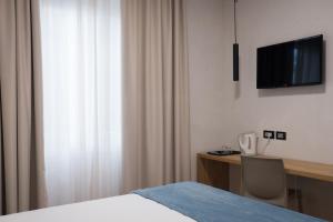 热那亚Hotel Doria的一间卧室配有一张床、一张书桌和一台电视