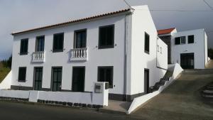 Castelo BrancoBELO CAMPO - Ilha do Faial (Horta)的白色的建筑,设有黑色的大门和窗户