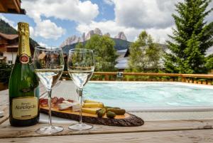 卡纳泽伊Hotel Cirelle Suite & Spa的游泳池旁托盘上放两杯葡萄酒和奶酪