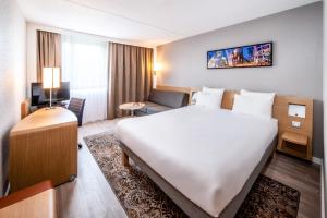 埃因霍温埃因霍温诺富特酒店的酒店客房设有一张大床和一张沙发。