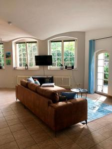 德累斯顿Ferienwohnung am Wasser Villa Graf von Pfeil的客厅设有一张棕色沙发,配有窗户
