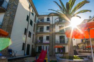 阿西亚罗利Acciaroli Vacanze Residence的一座棕榈树建筑和一座带遮阳伞的建筑