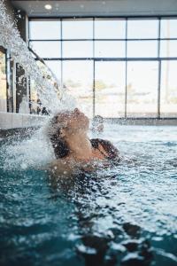 卡普费雷Domaine du Ferret Restaurant & Spa的游泳池里喷水的女人