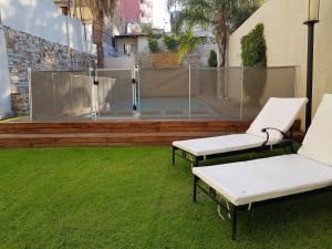 门多萨维拉吉奥精品酒店的两只白长椅坐在院子里的草地上
