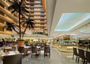 香港香港帝苑酒店的一间设有桌椅的餐厅,并种植了棕榈树