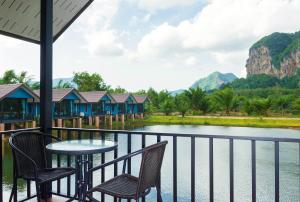 奥南海滩Baannai Lake View Resort的阳台配有桌椅,俯瞰着河流