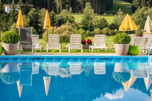 塞尔赖因山谷格里斯Bergsporthotel Antonie的一个带草坪椅和遮阳伞的游泳池