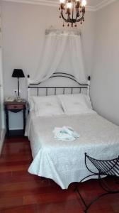塞维利亚巴黎乐派酒店的卧室配有白色的床和吊灯。