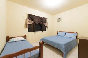 巴拉奈里奥-坎布里乌Pousada Dona Ema的一间卧室设有两张床,窗户配有窗帘