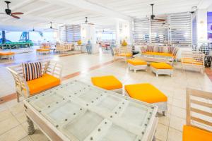 蒙特哥贝Grand Decameron Montego Beach, A Trademark All-Inclusive Resort的餐厅配有橙色和白色的椅子和桌子