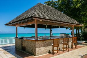 蒙特哥贝Grand Decameron Montego Beach, A Trademark All-Inclusive Resort的一个带两把椅子和屋顶的户外酒吧